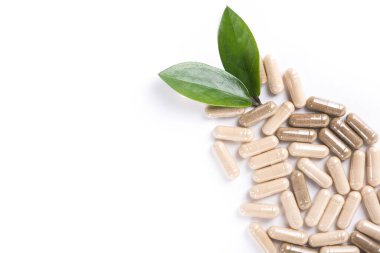 Beyaz arka planda yeşil yapraklı ilaç ve kapsül sürüsü. en üstteki görünüm