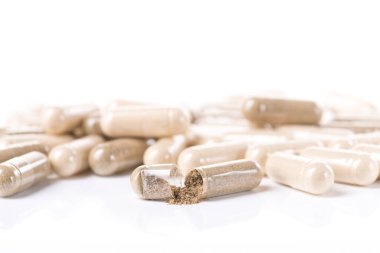 Sağlık bitkisel kapsülü beyaz arka planda izole edilmiş. Hapları barutla aç.