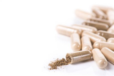 Sağlık bitkisel kapsülü beyaz arka planda izole edilmiş. Hapları barutla aç.