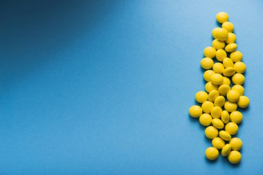 Mavi arka planda tıbbi sarı yuvarlak haplar.