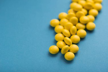 Mavi arka planda tıbbi sarı yuvarlak haplar.