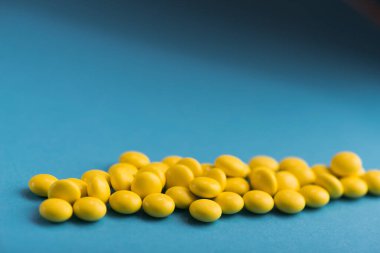 Mavi arka planda tıbbi sarı yuvarlak haplar.