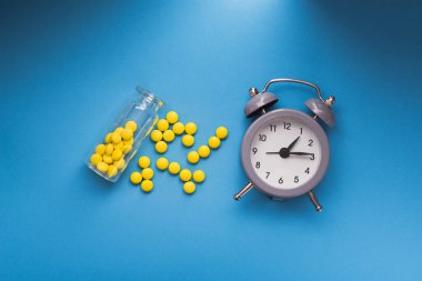 Mavi arkaplanlı sarı haplar. İlaç alma zamanı. en üstteki görünüm