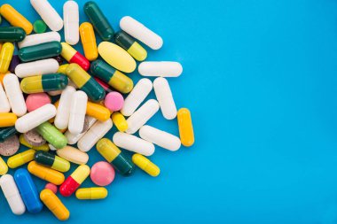 Mavi arka planda bir sürü renkli hap ve kapsül