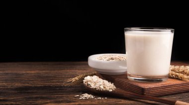 Tahta bir masada bir bardak yulaf sütü ve yulaf ezmesi. Vejetaryen diyet konsepti.