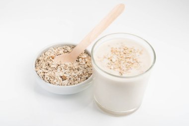 Beyaz arka planda izole edilmiş bir bardak yulaf sütü ve tahıl.
