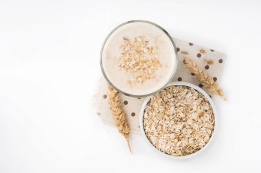 Beyaz arka planda izole edilmiş bir bardak yulaf sütü ve tahıl.