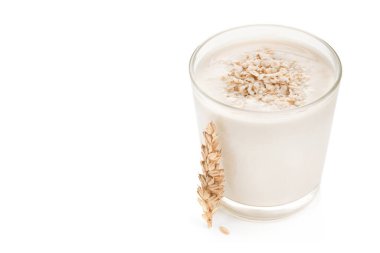 Beyaz arka planda izole edilmiş bir bardak yulaf sütü ve tahıl.