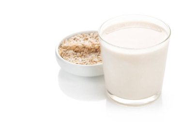 Beyaz arka planda izole edilmiş bir bardak yulaf sütü ve tahıl.