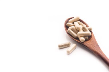 Beyaza izole edilmiş kaşıklı tıbbi bitkisel kapsüller. Doğal vitamin katkı hapları..