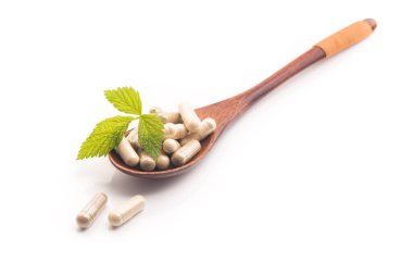 Yeşil yapraklı bitkisel tıbbi kapsül beyaz arka planda izole edilmiş. Doğal malzemeli haplar..