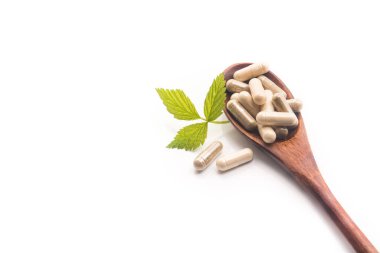 Beyaza izole edilmiş kaşıklı tıbbi bitkisel kapsüller. Doğal vitamin katkı hapları. en üstteki görünüm