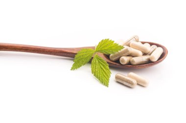 Yeşil yapraklı bitkisel tıbbi kapsül beyaz arka planda izole edilmiş. Doğal malzemeli haplar..