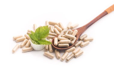 Yeşil yapraklı bitkisel tıbbi kapsül beyaz arka planda izole edilmiş. Doğal malzemeli haplar..