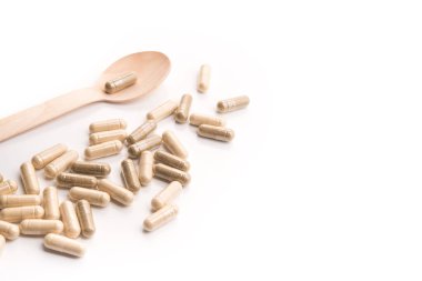 Beyaza izole edilmiş kaşıklı tıbbi bitkisel kapsüller. Doğal vitamin katkı hapları..