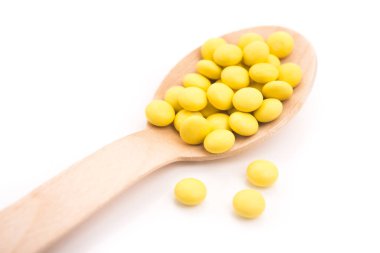 Sarı yuvarlak vitamin hapları beyaz arka planda izole edilmiş kaşıkta