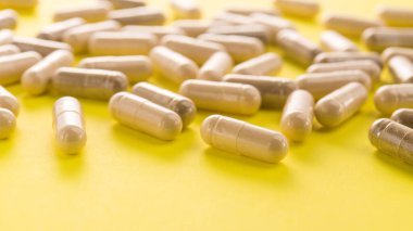 Sarı arka planda bitkisel tıbbi kapsül. Doğal vitamin takviyeleri.