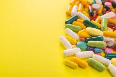 Sarı arka planda renkli kapsül hapları yığını. Parlak tıbbi fotoğraf.