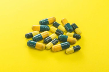 Sarı arka planda renkli kapsül hapları yığını. Parlak tıbbi fotoğraf.