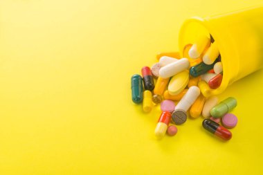 Sarı arka planda renkli kapsül hapları yığını. Parlak tıbbi fotoğraf.