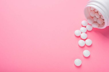 Pastel pembe arka planda beyaz haplar. Kadın tedavisi kavramı. Üst Manzara. metin için yer.