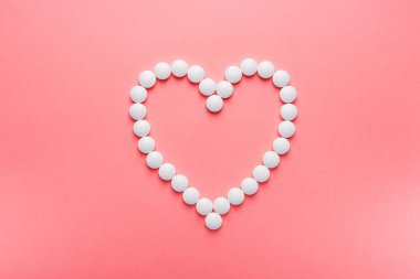 Beyaz kalp, haplardan ve pembe pastel arka plandaki haplardan yapılmış. en üstteki görünüm