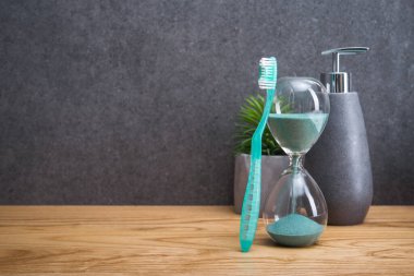 Tuvalet masasında kum saati olan diş fırçaları. Diş bakımı ve hijyen.