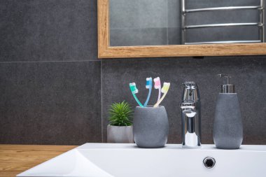 Beyaz seramik lavabo ve banyo aksesuarlarıyla banyo İskandinav usulü doğal ahşap masa..