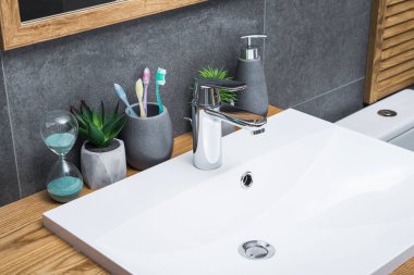 Beyaz seramik lavabo ve banyo aksesuarlarıyla banyo İskandinav usulü doğal ahşap masa..