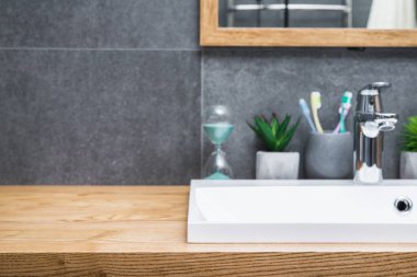 Beyaz seramik lavabo ve banyo aksesuarlarıyla banyo İskandinav usulü doğal ahşap masa. mesaj için yer. odak dışı