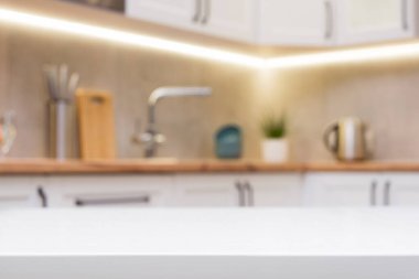 Beyaz ahşap bir masaya ve arka plana odaklanmadan İskandinav mutfağına odaklan..