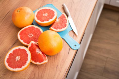 Mutfak ahşap masasında dilimlenmiş sulu greyfurt parçaları..