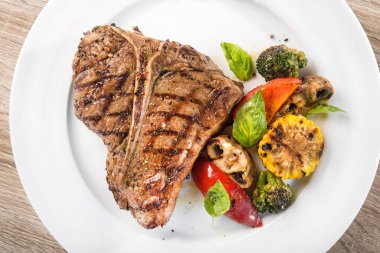 Beyaz tabakta sebzeli ızgara biftek. en üstteki görünüm