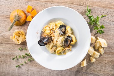 Tahta bir masada midyeli, parmesanlı ve balkabaklı lezzetli ravioli makarnası. en üstteki görünüm