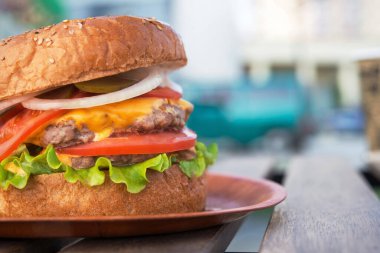 Lezzetli ve sulu burger, biftek ve domates, masada peynir. sokak fast food geçmişi