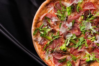 Siyah arka planda pastırmalı ve sebzeli İtalyan pizzası..