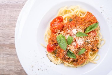 Beyaz tabakta dana eti ve fesleğen yapraklı spagetti bolonez. en üstteki görünüm