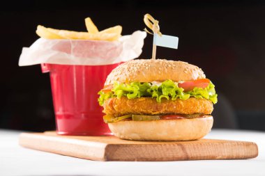 Arkaplanda izole edilmiş tahtanın üzerinde hamburger ve patates kızartması.