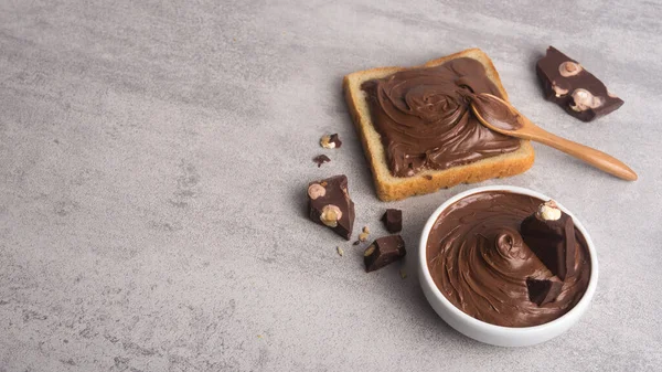 Coklat Menyebar Atas Sepotong Roti Dengan Sendok Mangkuk Putih Krim — Stok Foto