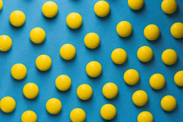 Mavi arka planda tıbbi sarı yuvarlak haplar.