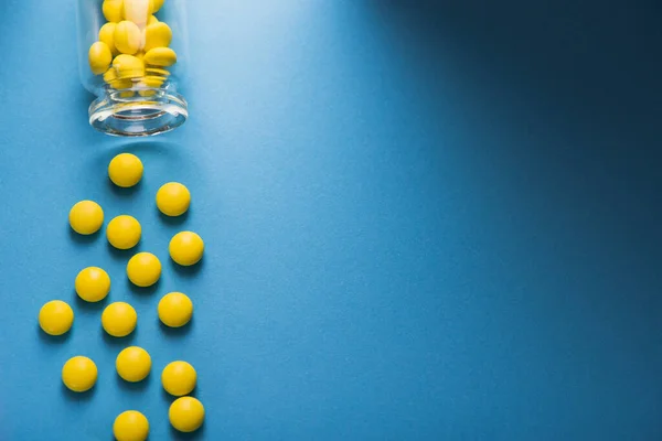 Żółte Tabletki Witaminowe Butelką Niebieskim Tle Widok Góry — Zdjęcie stockowe
