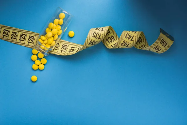 Желтые Круглые Витаминные Таблетки Измерительной Лентой Синем Фоне Концепция Потери — стоковое фото