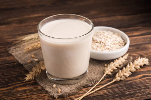 Tahta bir masada bir bardak yulaf sütü ve yulaf ezmesi. Vejetaryen diyet konsepti. Popüler ve moda yemekler. laktozsuz