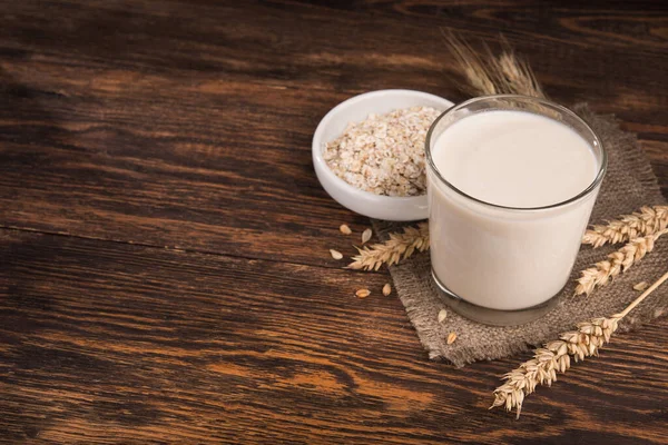 Tahta bir masada bir bardak yulaf sütü ve yulaf ezmesi. Vejetaryen diyet konsepti.