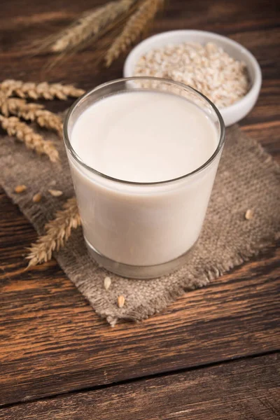Tahta bir masada bir bardak yulaf sütü ve yulaf ezmesi. Vejetaryen diyet konsepti. Popüler ve trend yiyecek.
