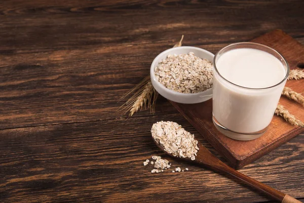 Tahta bir masada bir bardak yulaf sütü ve yulaf ezmesi. Vejetaryen diyet konsepti. Popüler ve trend yiyecek.