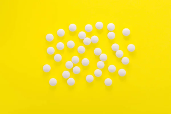 黄色背景的白色医疗药丸和药片 顶部视图 — 图库照片