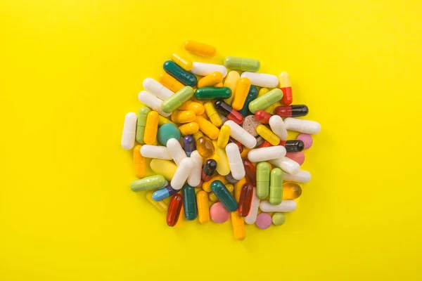 stock image Pile of colored capsule pills on a yellow background. Bright medical photo.