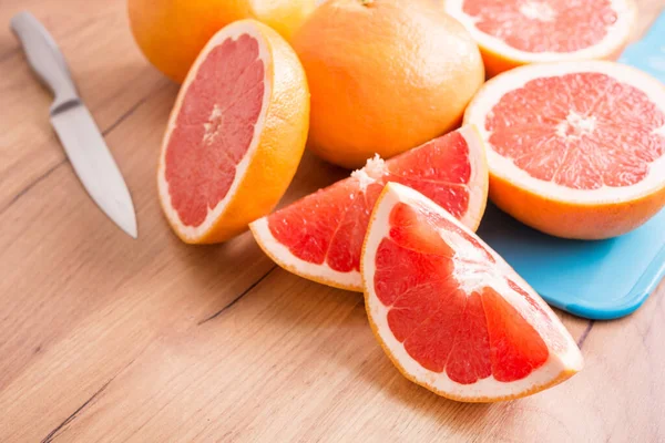 Mutfak ahşap masasında dilimlenmiş sulu greyfurt parçaları..