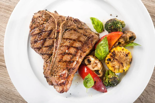 Beyaz tabakta sebzeli ızgara biftek. en üstteki görünüm